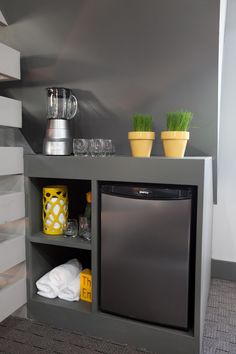 a kitchen area with a refrigerator, dishwasher and two cups on the shelf