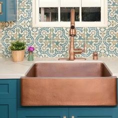 a copper sink in a blue and white kitchen