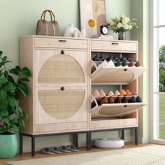 a wooden cabinet with shoes on it next to a potted plant and large window