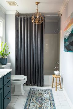 a white toilet sitting next to a bath tub in a bathroom under a chandelier