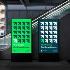 two green signs with arrows on them in front of an escalator and stairs