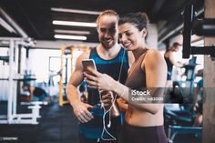 a man and woman in the gym looking at a cell phone while standing next to each other