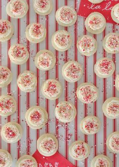 cupcakes with white frosting and sprinkles on a red and white striped background