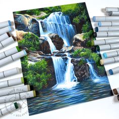 there are many crayons next to the drawing of a waterfall