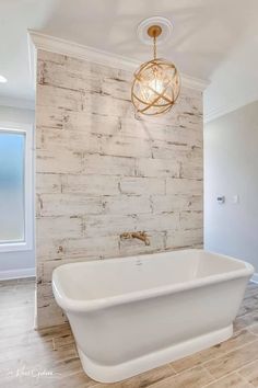 a large white bath tub sitting under a light fixture in a bathroom next to a window