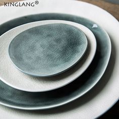 three white and gray plates sitting on top of a wooden table next to each other