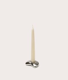 a white candle sitting on top of a metal spoon