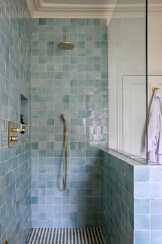 a bathroom with blue tiles on the walls and floor, shower head is in the corner