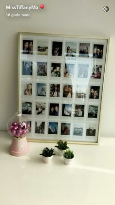 a white table topped with pictures and plants next to a vase filled with pink flowers