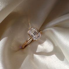 an engagement ring is sitting on a white cloth with the light reflecting off it's face