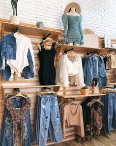 clothes are displayed on wooden shelves in a store