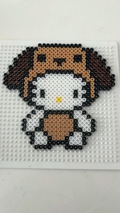 an image of a beaded hello kitty on a white surface with black and brown beads