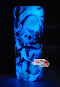 a blue glass with an image of skulls and flowers on it is lit up in the dark