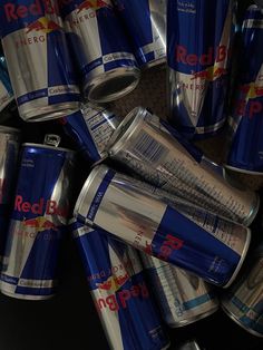 several cans of red bull energy drink stacked on top of each other in a pile