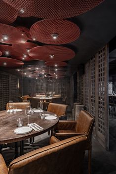 a dining room with chairs, tables and wine bottles hanging from the ceiling above it