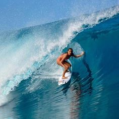 a woman riding a wave on top of a surfboard in the ocean with blue water