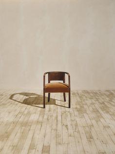 a chair sitting on top of a wooden floor next to a white wall with a shadow