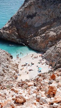 people are on the beach near rocks and water