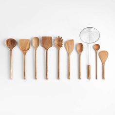 wooden utensils lined up in a row on a white background with a wire strainer