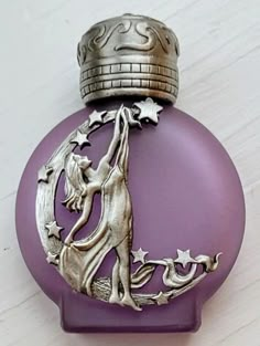 a purple perfume bottle with a silver cap on it's top sitting on a white surface