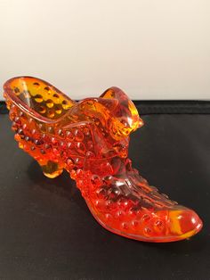 an orange glass shoe sitting on top of a table