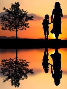 a mother and child holding hands as the sun sets