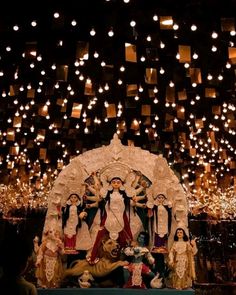 a group of people standing on top of a stage with lights hanging from the ceiling