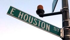 the street sign for e houston st is clearly visible in this photo, with an orange traffic light at the top