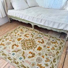 a white couch sitting on top of a wooden floor next to a rug covered in pillows