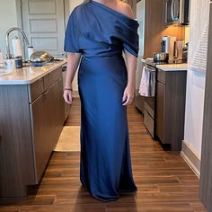 a woman standing in a kitchen wearing a blue dress