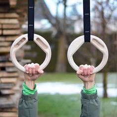 two hands holding up rings in front of a building with snow on the ground behind them