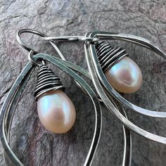 A pair of genuine freshwater pearls are carefully wrapped in sterling silver wire. The luminous pearls are very pale peach in color. The pair is framed by sterling silver petal shapes which I have formed, soldered, and textured by hand. The earrings hang from handformed Sterling Silver earwires. The silver has been oxidized and polished to create the patina finish. Be sure to see all photos and video for size and color reference. Total Earring Length: About 1 and 3/4" Elegant Handmade Peach Jewelry, Handmade Silver Pearl Earrings In Pear Shape, Handmade Silver Pear-shaped Pearl Earrings, Delicate Teardrop Wire Wrapped Pearl Earrings, Silver Teardrop Wire Wrapped Pearl Earrings, Pale Peach, Color Reference, Patina Finish, Handmade Sterling Silver