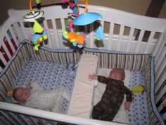 a baby laying in a crib with stuffed animals hanging from it's sides