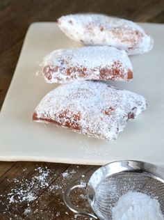 three powdered sugar pastries on a white plate