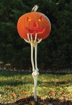 a jack - o'- lantern is standing in the grass with it's arms and legs sticking out