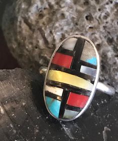 Vintage sterling Zuni ring with stone to stone inlay of coral, turquoise, shell, and onyx. There are slight gaps in places in the inlay. The ring is interesting, and I believe old. The artisan has chosen to include more gray matrix than turquoise in one panel. This is a soulful and colorful little artisan made ring. The ring is size 6-1/4. The face of the ring is .75 inches long and .47 inches wide. It weighs 3 grams. Handmade Artisan Multicolor Turquoise Ring, Handmade Multicolor Artisan Turquoise Ring, Artisan Oval Multi-stone Turquoise Ring, Artisan Multicolor Turquoise Ring With Natural Stones, Artisan Multicolor Turquoise Ring, Handmade Multicolor Southwestern Turquoise Ring, Artisan Multicolor Ring Jewelry, Multicolor Oval Inlay Rings, Unique Oval Multi-stone Turquoise Ring