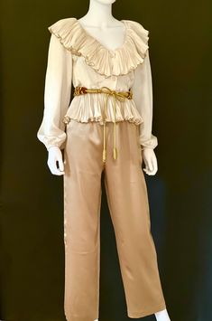 "STUNNING vintage C1970s high end, off white or ivory sumptuous long sleeve silk blouse by Partique, featuring a lavish V neck collar with pleated ruffles fully edged in gold trim, a peplum hem, also with pleated ruffles fully edged in gold trim, and a three button front closure.  Channeling Old Hollywood elegance and glamour, this rare beauty is a guaranteed head turner! Approximate Measurements:      Chest: 38\"; Shoulder: 16\"; Waist: 27\"; Length: 19 1/2\"      Labeled a Size 6 Please Note: V Neck Collar, First Ladies, Party Blouse, American Fashion Designers, Rare Beauty, Ivory Silk, American Fashion, Peplum Hem, Silk Pants