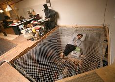 a man laying on top of a metal cage in a room filled with clutter