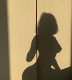 the shadow of a woman's head and arm on a wall behind a pole