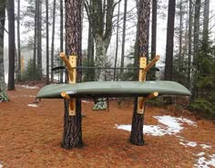 two canoes sitting on top of trees in the woods with snow around them,