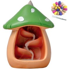 a green and orange mushroom shaped object next to a pen holder with colored pencils in it