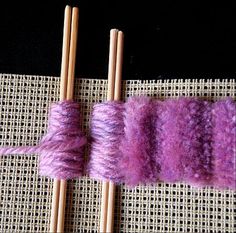 two skewers with yarn on them sitting next to each other in front of a piece of cloth