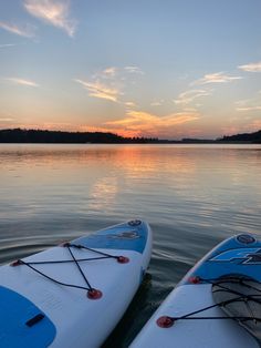 two kayaks sitting in the water at sunset