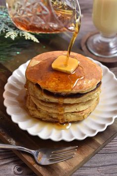 a stack of pancakes with syrup being poured on top