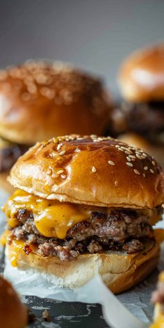 three cheeseburgers sitting next to each other on wax paper