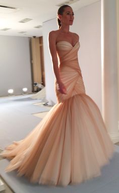 a woman in an orange dress standing on a runway