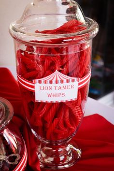 a glass jar filled with red yarn on top of a table