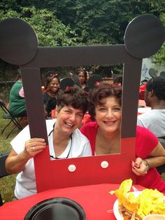 two people sitting at a table in front of a mickey mouse frame with food on it