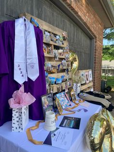 a table with purple and white graduation gowns on display at an outdoor event in front of a building