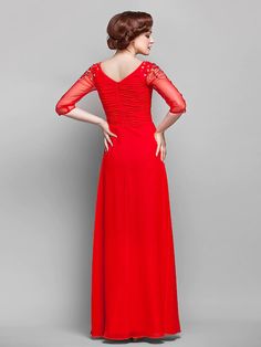 a woman in a long red dress with sleeves on her back and shoulder, standing against a